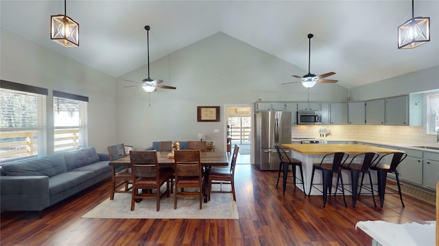 dining area with high vaulted ceiling, dark wood-type flooring, sink, and ceiling fan