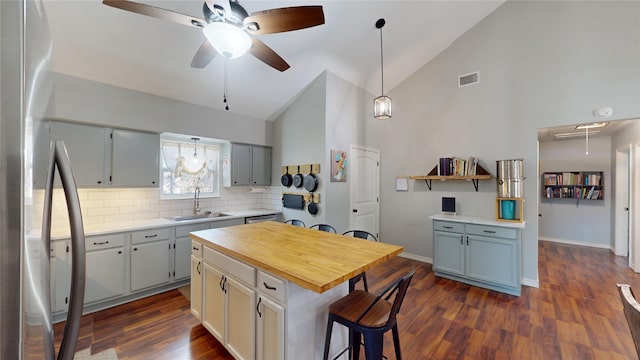 kitchen with ceiling fan, decorative backsplash, stainless steel refrigerator, a kitchen island, and sink