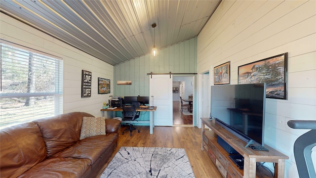 living room with wood ceiling, a barn door, wood walls, light wood-type flooring, and vaulted ceiling