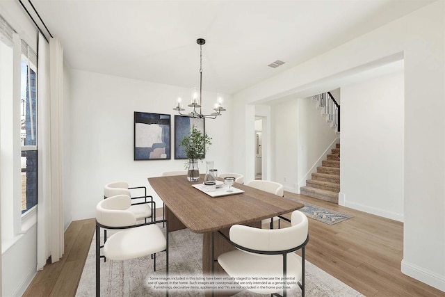 dining area featuring visible vents, light wood finished floors, baseboards, a chandelier, and stairs