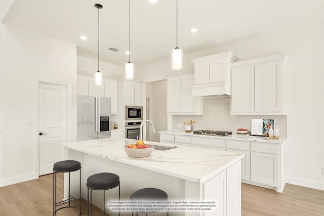 kitchen with visible vents, a sink, stainless steel appliances, white cabinets, and tasteful backsplash