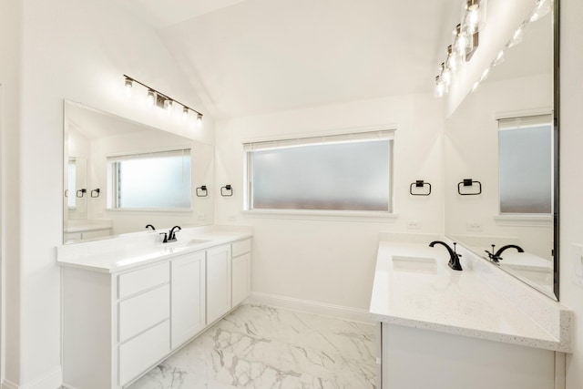 full bath with two vanities, marble finish floor, a sink, baseboards, and vaulted ceiling