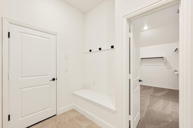 mudroom with light tile patterned floors, light colored carpet, and baseboards