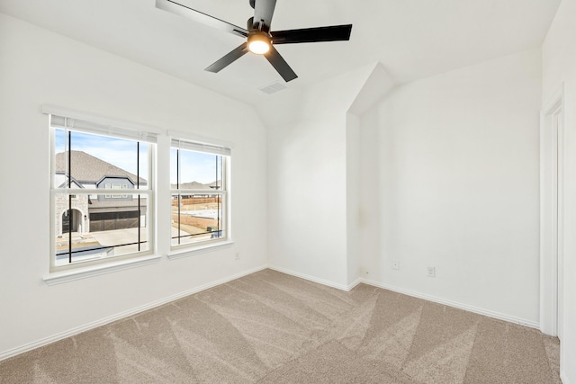 carpeted spare room with vaulted ceiling, a ceiling fan, baseboards, and visible vents