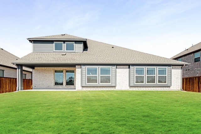 back of house with a lawn, a fenced backyard, brick siding, and a shingled roof