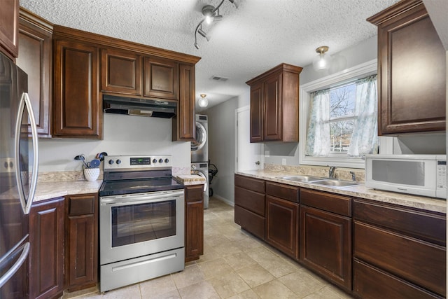 kitchen with dark brown cabinetry, stacked washer and clothes dryer, sink, a textured ceiling, and stainless steel appliances