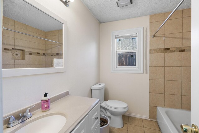 full bathroom featuring vanity, tile patterned floors, tiled shower / bath, toilet, and a textured ceiling