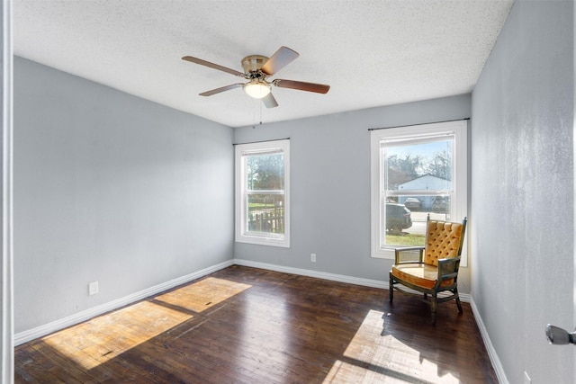 sitting room with ceiling fan, dark hardwood / wood-style floors, and a textured ceiling