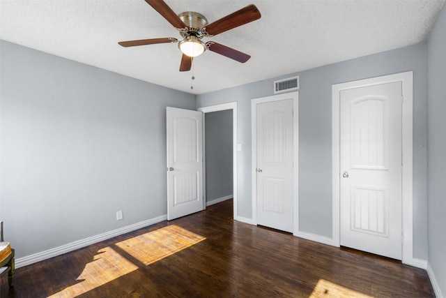 unfurnished bedroom featuring ceiling fan, dark hardwood / wood-style flooring, and a textured ceiling