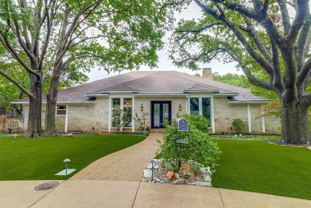 ranch-style home featuring french doors and a front lawn