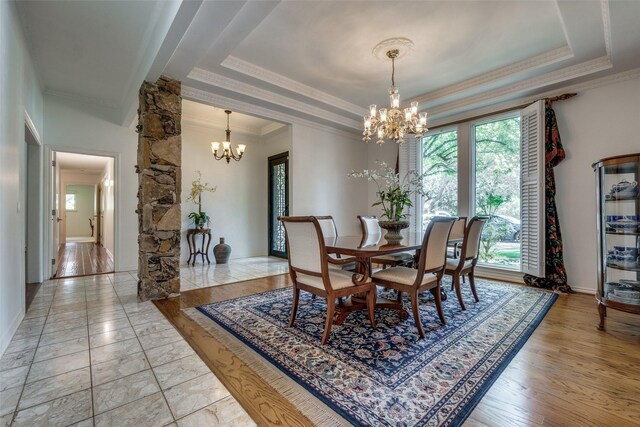 dining room with a raised ceiling, an inviting chandelier, and ornamental molding