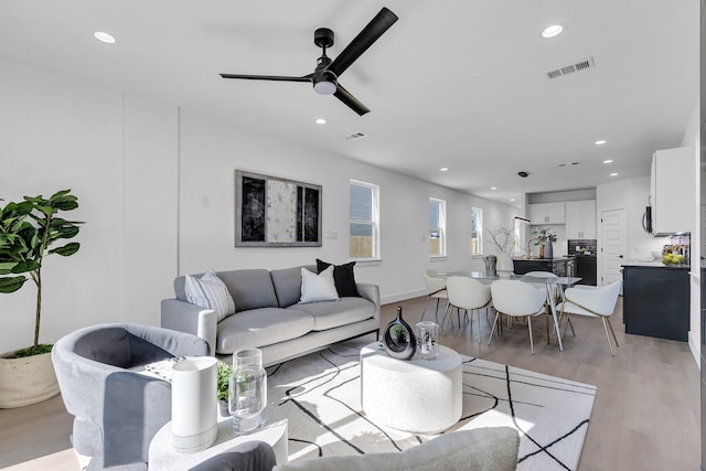 living room featuring ceiling fan and light hardwood / wood-style floors