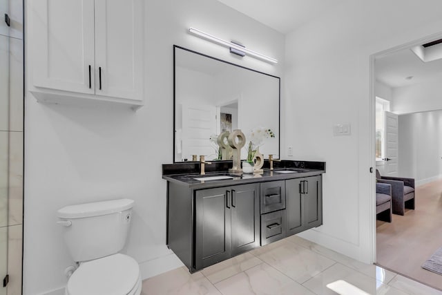 bathroom featuring double vanity, a sink, toilet, and baseboards