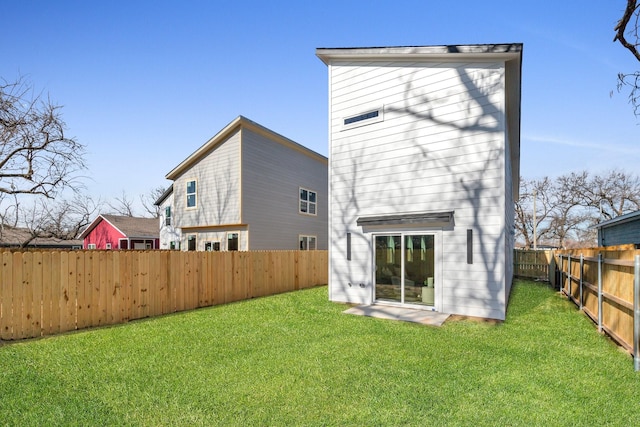 back of house with a lawn and a fenced backyard