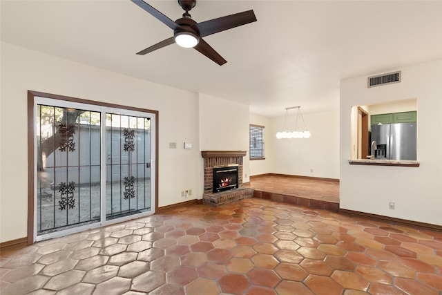 unfurnished living room featuring a brick fireplace and ceiling fan