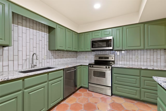 kitchen featuring decorative backsplash, sink, green cabinetry, and appliances with stainless steel finishes