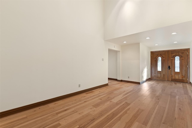 foyer entrance with a towering ceiling and light hardwood / wood-style floors