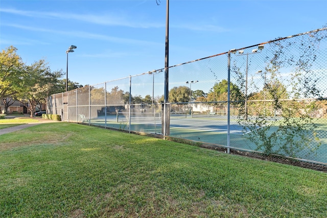 view of tennis court featuring a yard