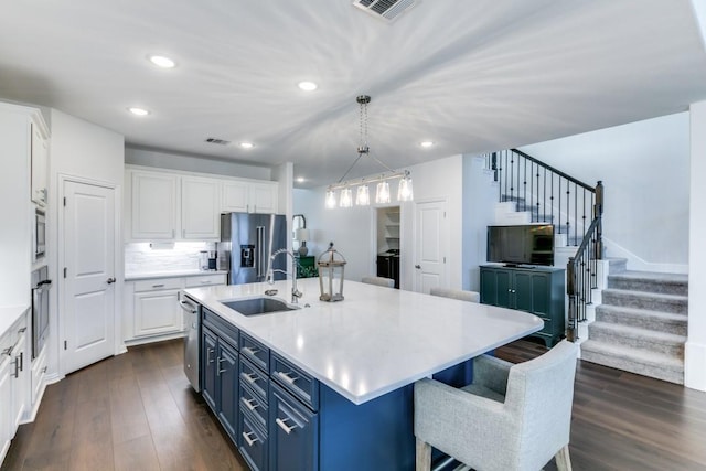 kitchen featuring stainless steel appliances, blue cabinets, white cabinetry, and sink