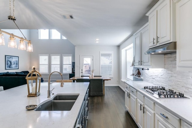 kitchen featuring pendant lighting, stainless steel gas stovetop, backsplash, white cabinets, and sink