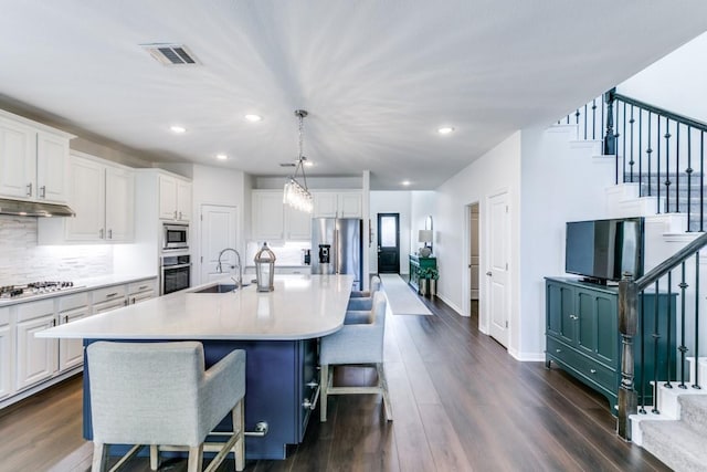 kitchen with decorative light fixtures, a large island, a breakfast bar area, appliances with stainless steel finishes, and white cabinetry