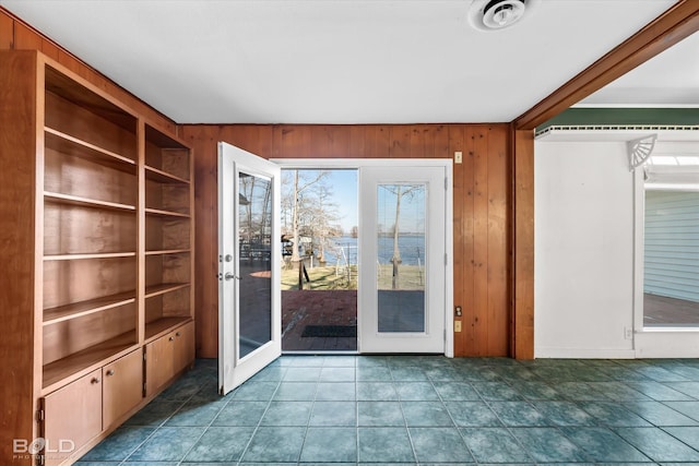 doorway to outside with wood walls, french doors, and dark tile patterned floors