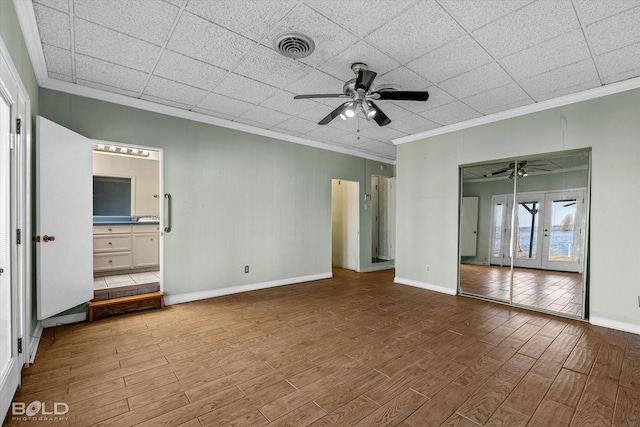 unfurnished bedroom featuring ceiling fan, a closet, crown molding, and french doors