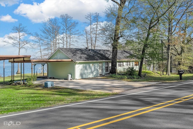 view of front of house with a front lawn, a water view, and a carport