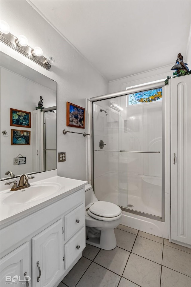 bathroom featuring tile patterned floors, vanity, toilet, and a shower with shower door