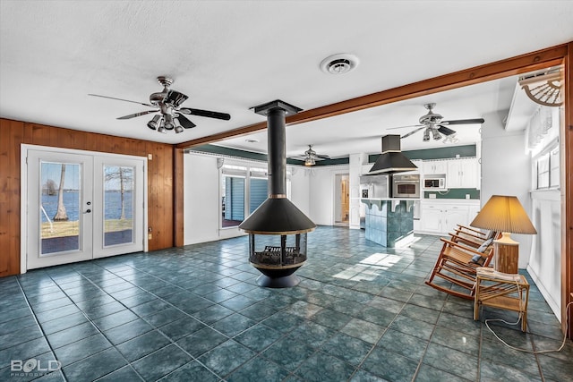 living room featuring wood walls, plenty of natural light, and a wood stove