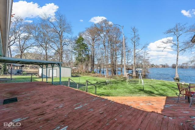 deck featuring a yard, a water view, and a storage unit