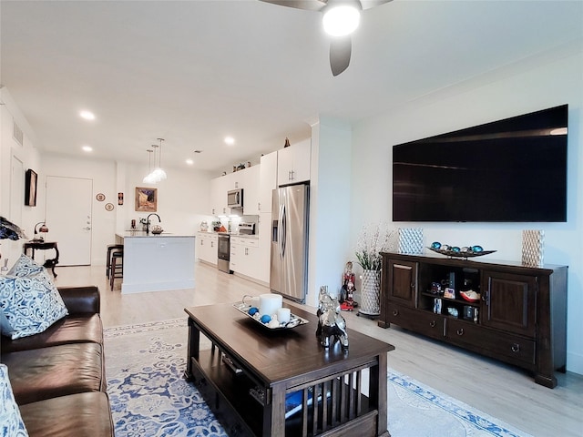 living room with light hardwood / wood-style floors, ceiling fan, and sink