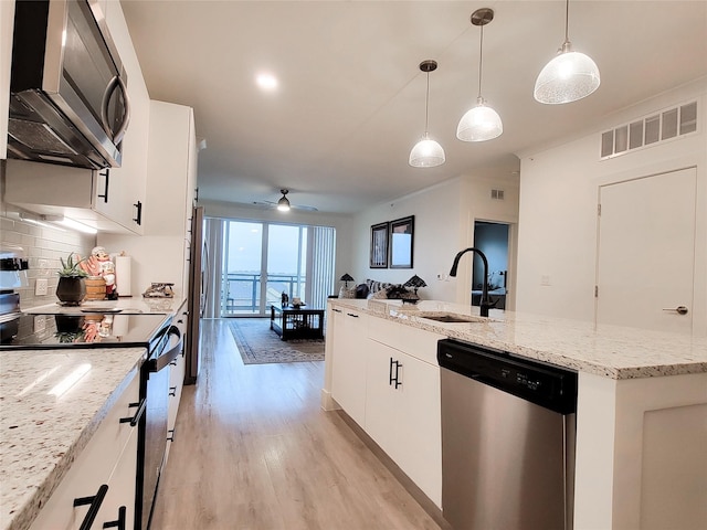 kitchen with stainless steel appliances, sink, a center island with sink, white cabinets, and hanging light fixtures