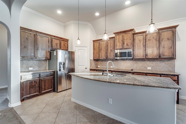 kitchen featuring sink, decorative light fixtures, stainless steel appliances, and a center island with sink