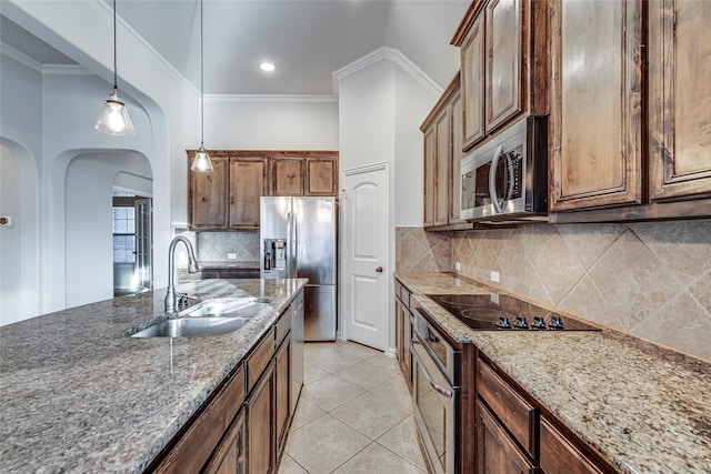 kitchen featuring sink, hanging light fixtures, stainless steel appliances, ornamental molding, and light stone countertops