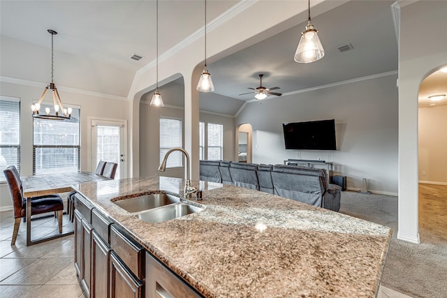 kitchen with decorative light fixtures, sink, and a center island with sink