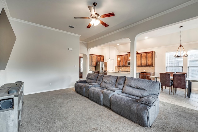 living room featuring light carpet, sink, ceiling fan with notable chandelier, and ornamental molding