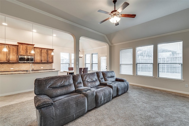 tiled living room featuring ornamental molding, lofted ceiling, sink, and ceiling fan