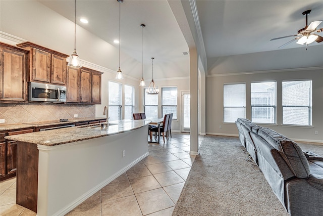 kitchen featuring vaulted ceiling, decorative light fixtures, sink, and a center island with sink