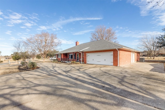 ranch-style home with a garage, a porch, and central air condition unit