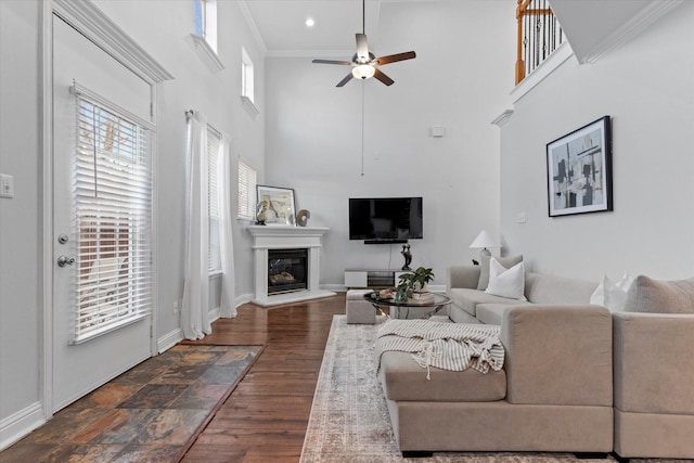 living room with ceiling fan, a high ceiling, and ornamental molding