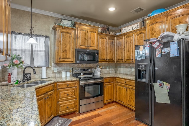 kitchen with decorative backsplash, sink, black appliances, decorative light fixtures, and light hardwood / wood-style floors