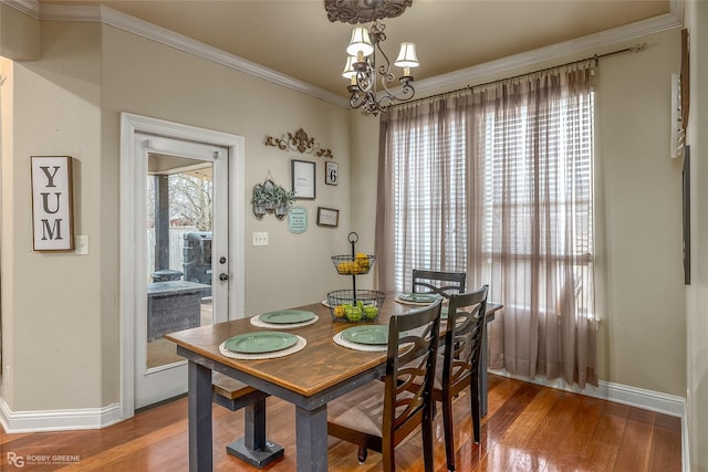 dining room with wood-type flooring, ornamental molding, and a notable chandelier