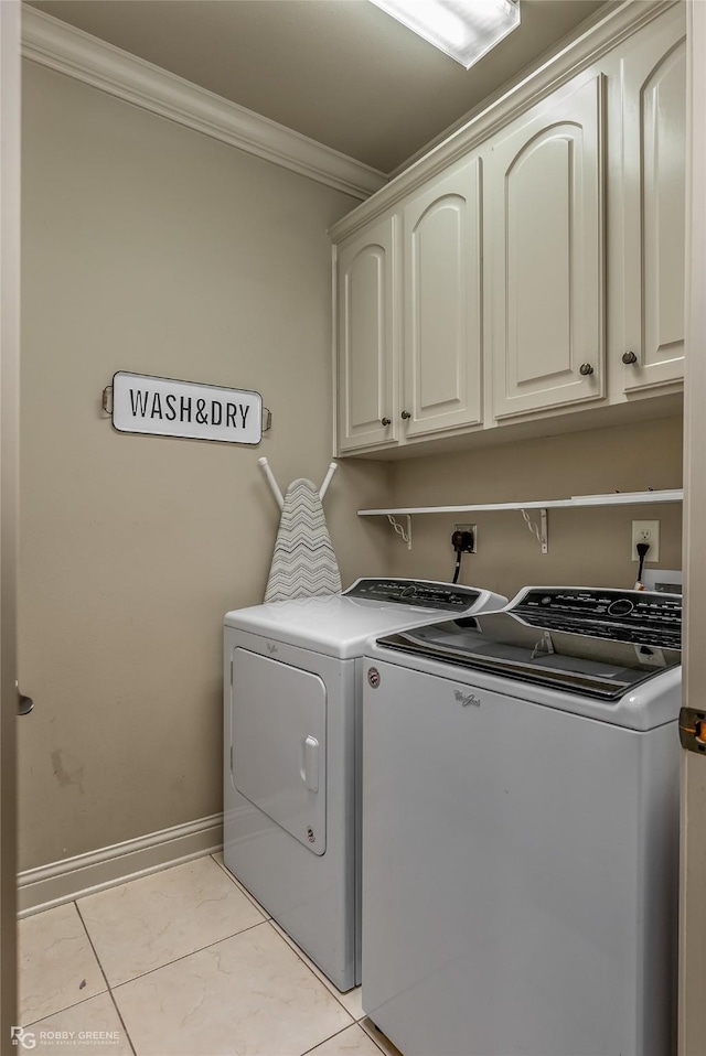 laundry room featuring washer and clothes dryer, cabinets, light tile patterned floors, and ornamental molding