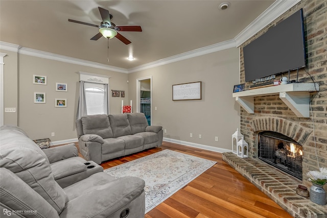 living room featuring crown molding, hardwood / wood-style floors, ceiling fan, and a brick fireplace