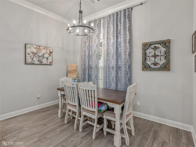 dining space with wood-type flooring, an inviting chandelier, and ornamental molding