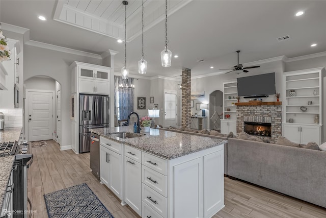 kitchen featuring white cabinets, a brick fireplace, and an island with sink