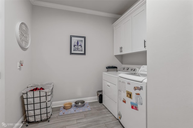 laundry area featuring crown molding, washer and clothes dryer, and cabinets