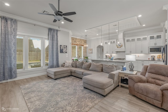 living room featuring ceiling fan, light hardwood / wood-style floors, and crown molding