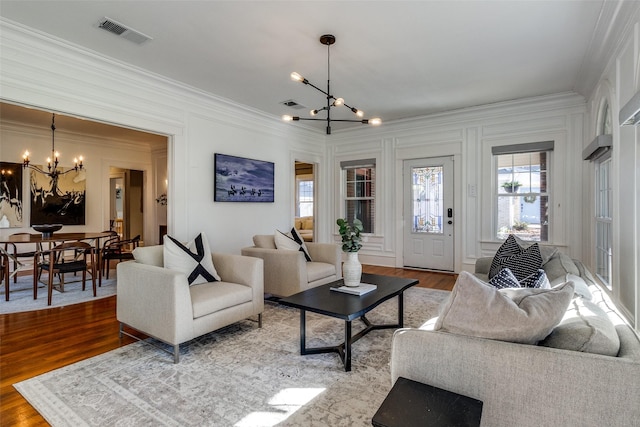 living room with a chandelier, wood-type flooring, and ornamental molding